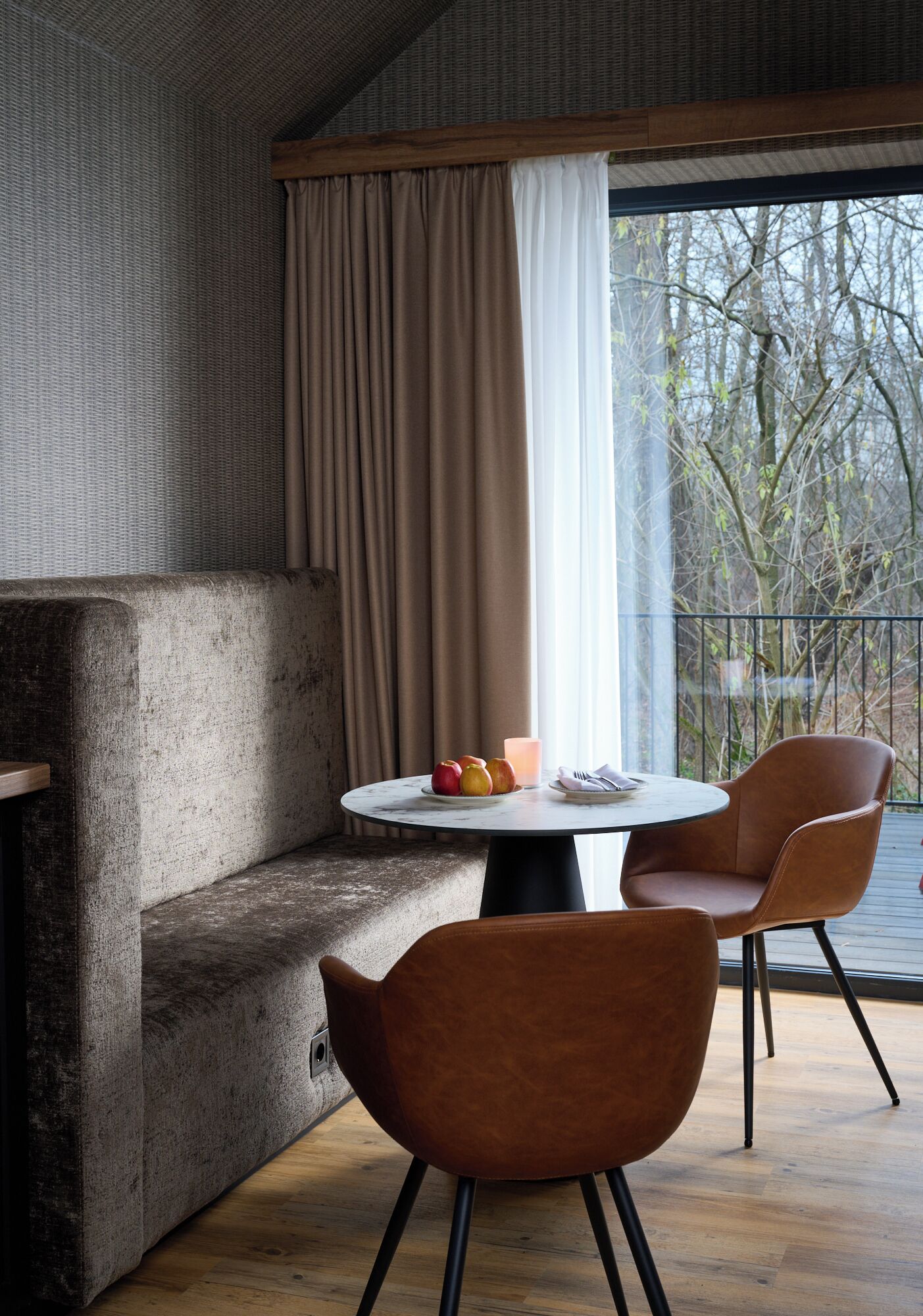 A modern room with a sofa, two chairs, a round table, and a large window with curtains.