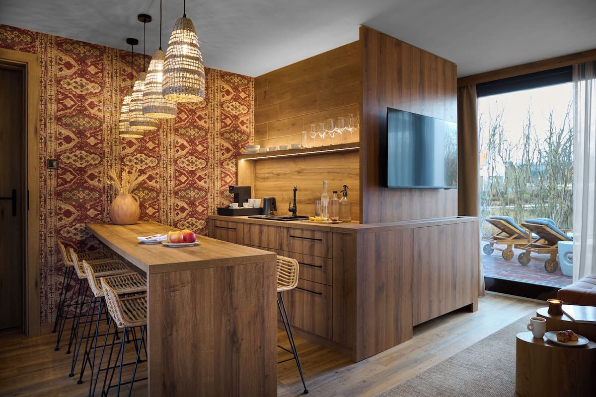 A modern kitchen with a wooden island, bar stools, and a large window overlooking a garden.
