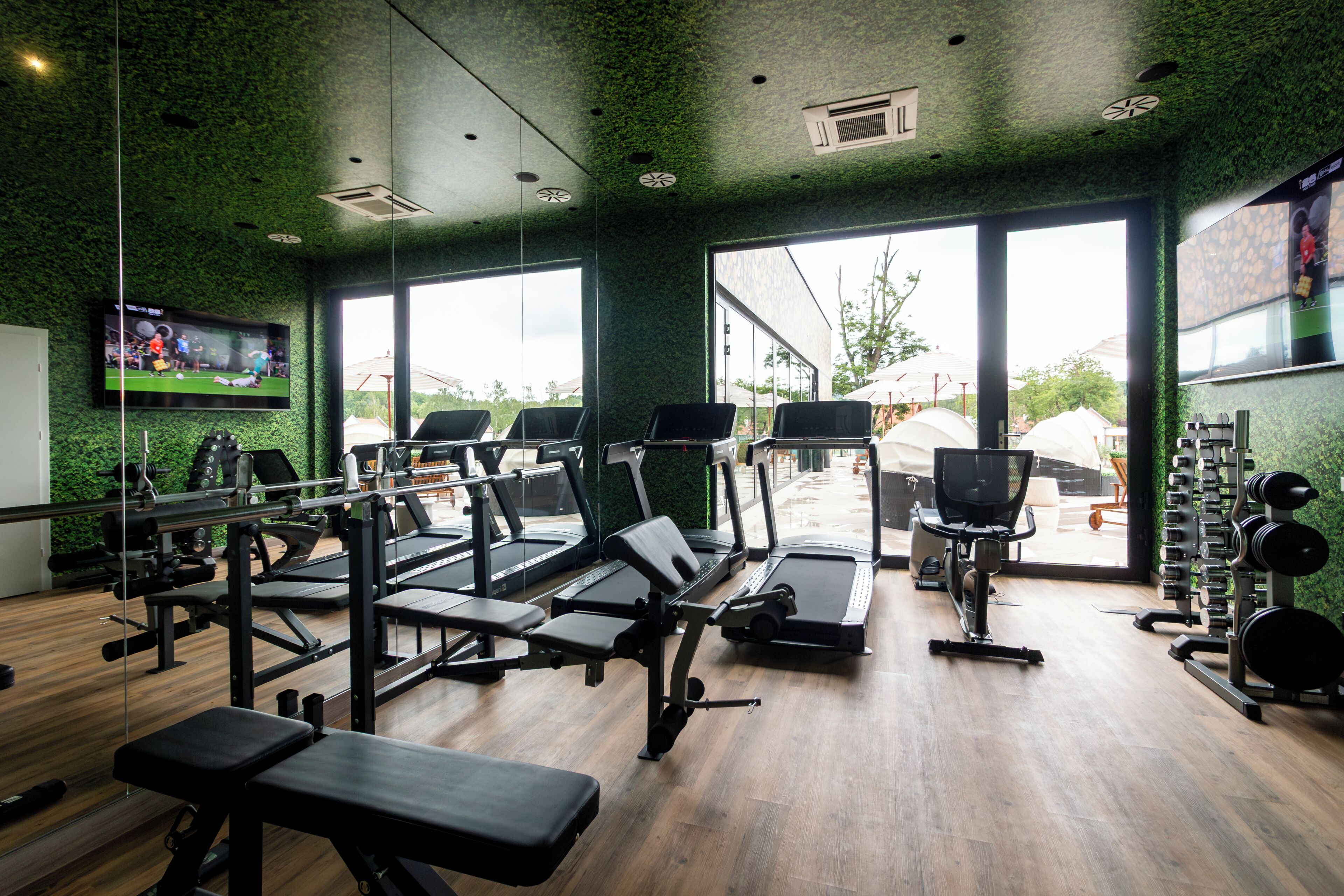 Un gimnasio con cintas de correr, máquinas de pesas y una pantalla de televisión.