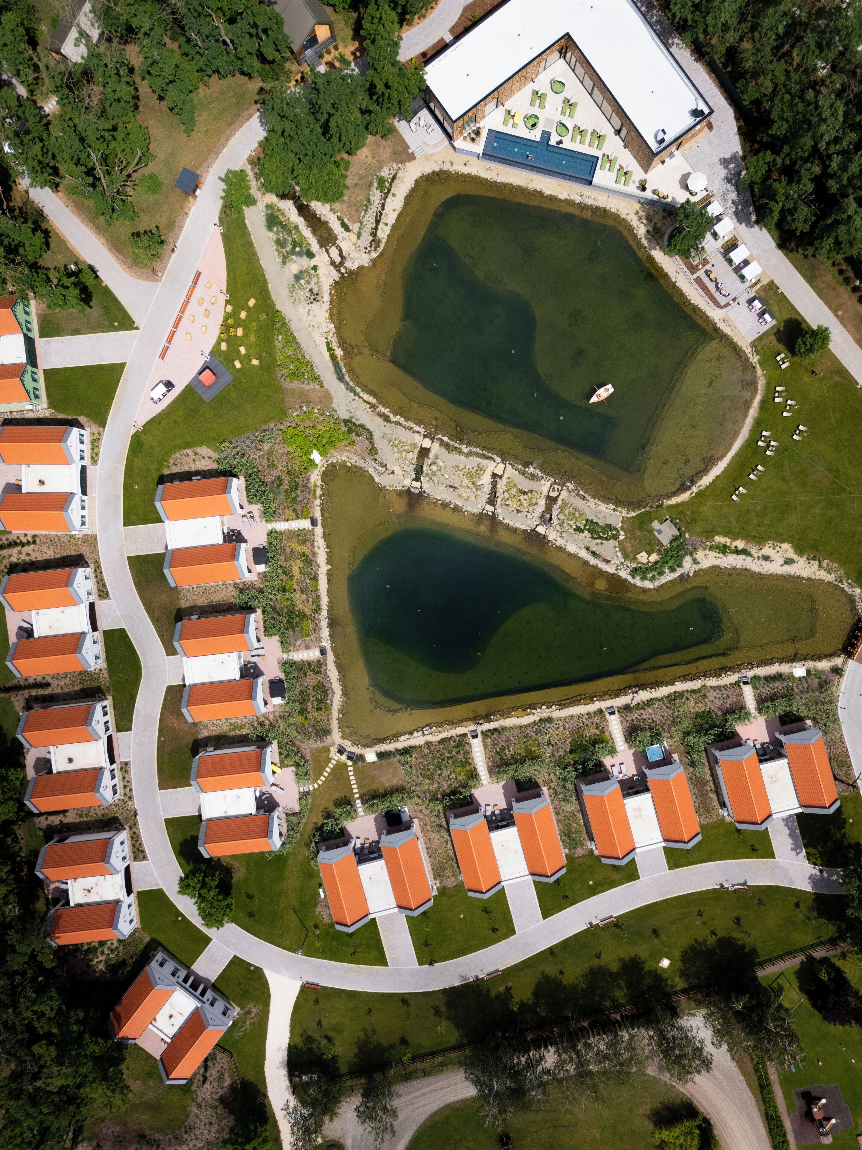 Vista aérea de una zona residencial con estanques con forma de corazón, una piscina y un hotel con terraza en la azotea.