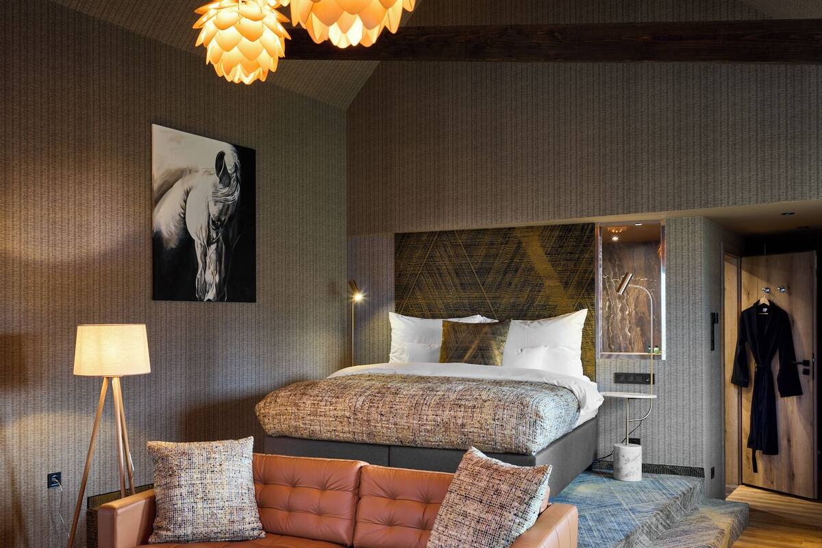 A modern bedroom with a large bed, a leather sofa, and a unique ceiling light fixture.