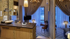 A modern bathroom with a large wooden vanity, a stone accent wall, and a large mirror.