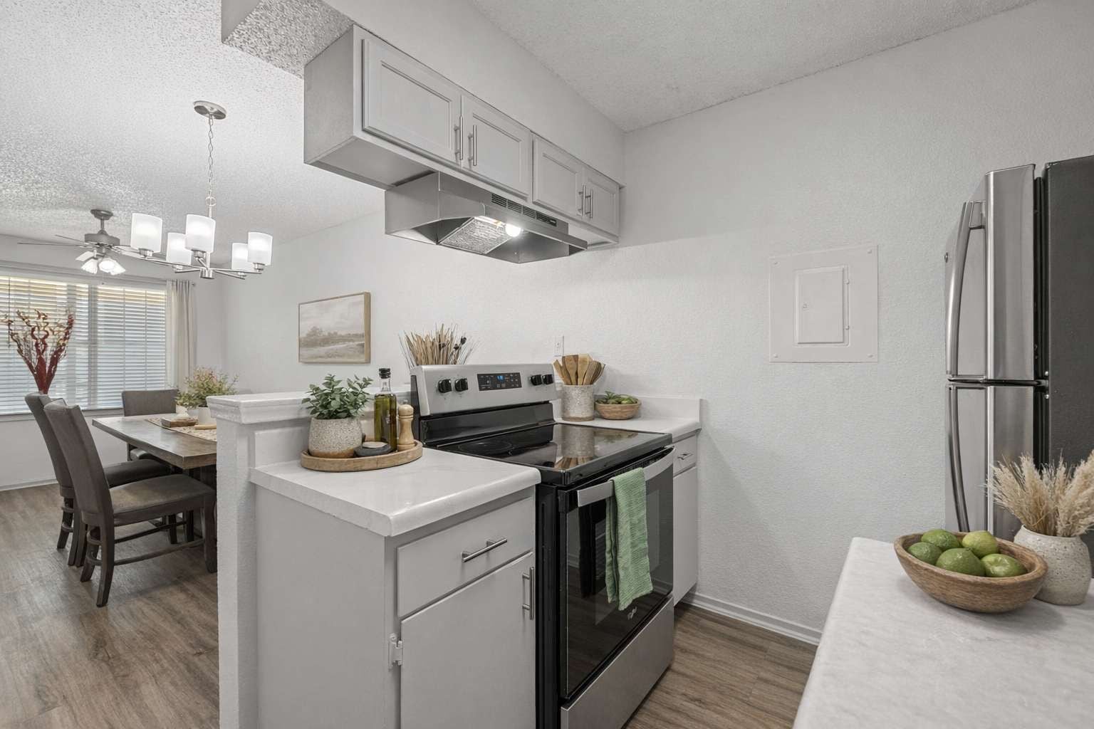 Una cocina moderna con una isla central, electrodomésticos de acero inoxidable y un comedor con candelabro.