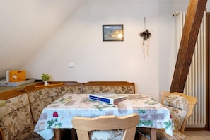 A dining area with a table covered in a floral tablecloth, a book on the table, and a plant on the sideboard. - Studio 7 with Mountain View, Barbecue Area and Wi-Fi (Oberharmersbach)