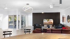 Una sala de estar moderna con un televisor grande, sofás de cuero y una zona de comedor.