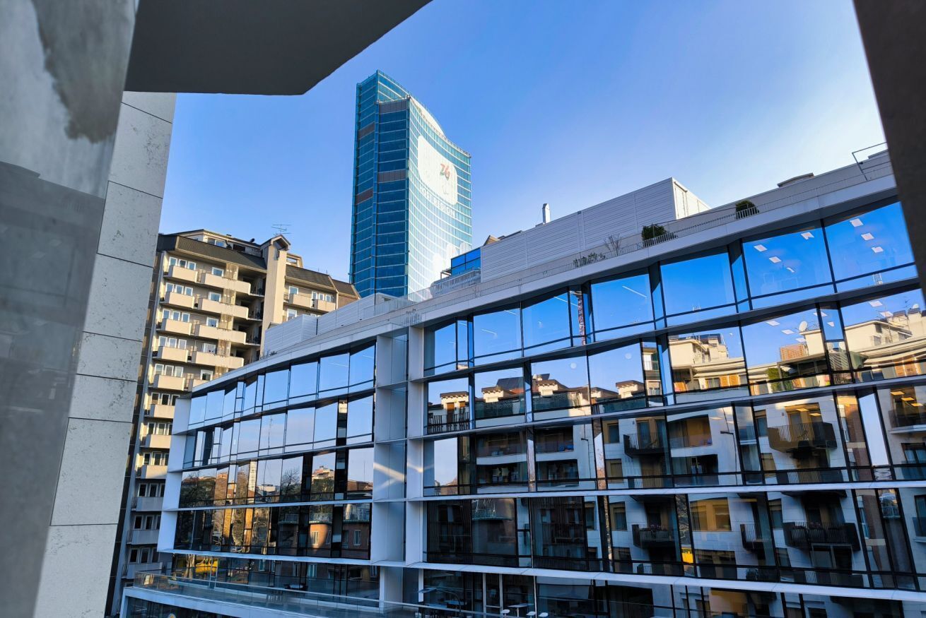 A modern building with multiple floors, large windows, and balconies.