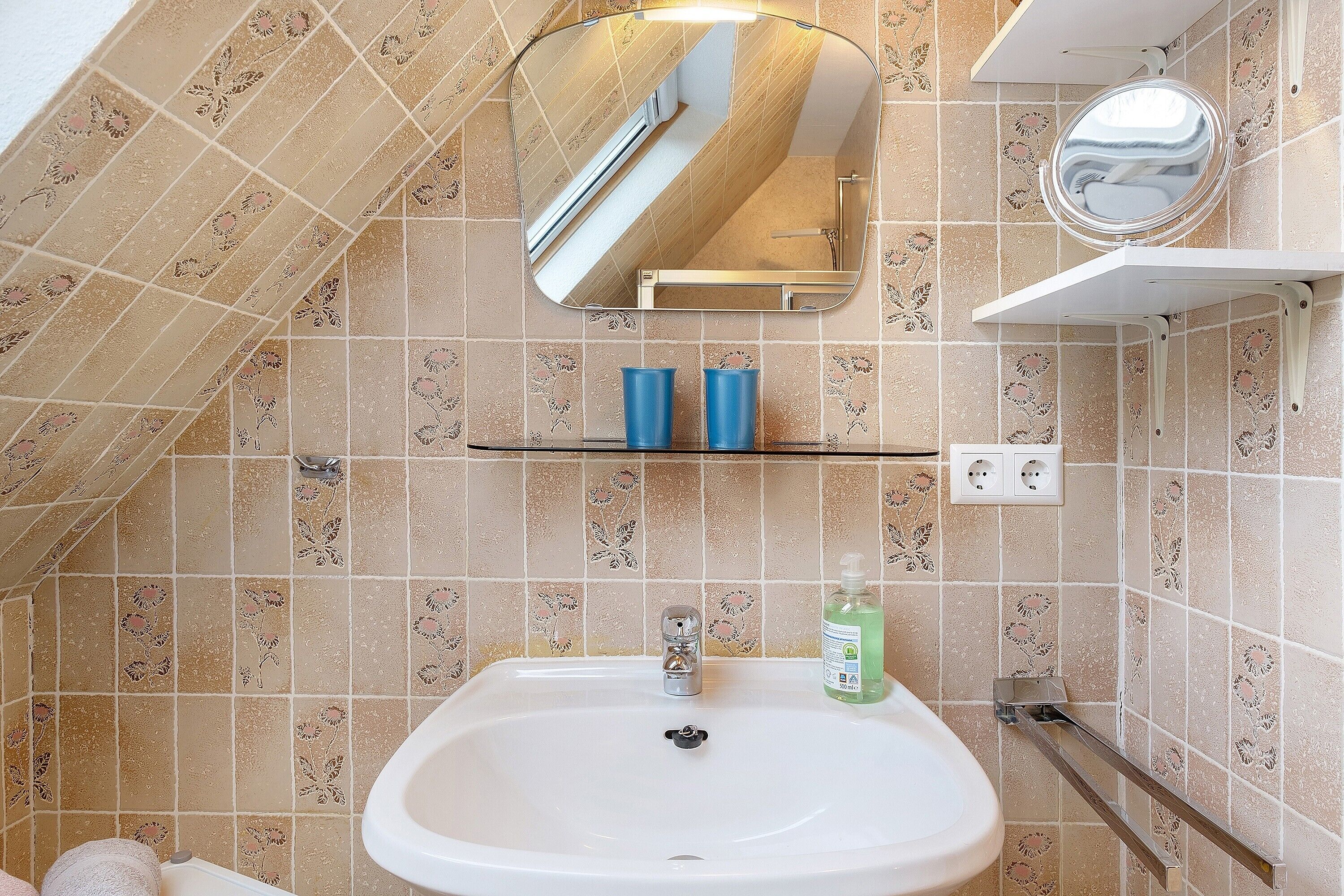 A bathroom with a sink, mirror, and shower.