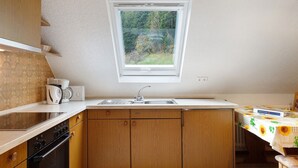 A kitchen with wooden cabinets, a built-in oven, a sink, and a window with a view of greenery. - Studio 8 with Barbecue Area and Wi-Fi (Oberharmersbach)