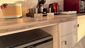 A kitchen with a coffee maker, kettle, and microwave on the counter.