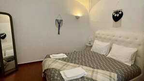 A bedroom with a bed, a mirror, a wall-mounted light, and a decorative heart-shaped item.