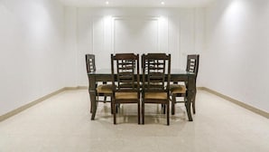 A dining area with a rectangular table surrounded by six wooden chairs with cushioned seats. - hotel aiims 20 four 7 (New Delhi)