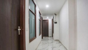 A hallway with marble flooring, wooden doors, and a ceiling light fixture. - hotel aiims 20 four 7 (New Delhi)
