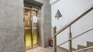 An elevator with a glass door, a fire extinguisher, and a metal handrail. - hotel aiims 20 four 7 (New Delhi)