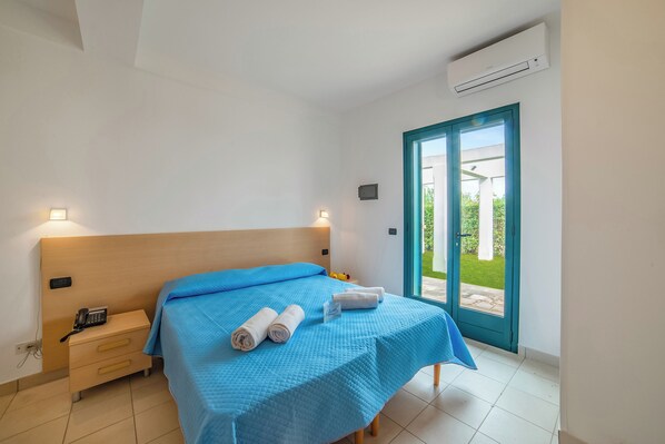 A bedroom with a bed, bedside table, and an air conditioning unit. - Blumare Resort (Otranto)