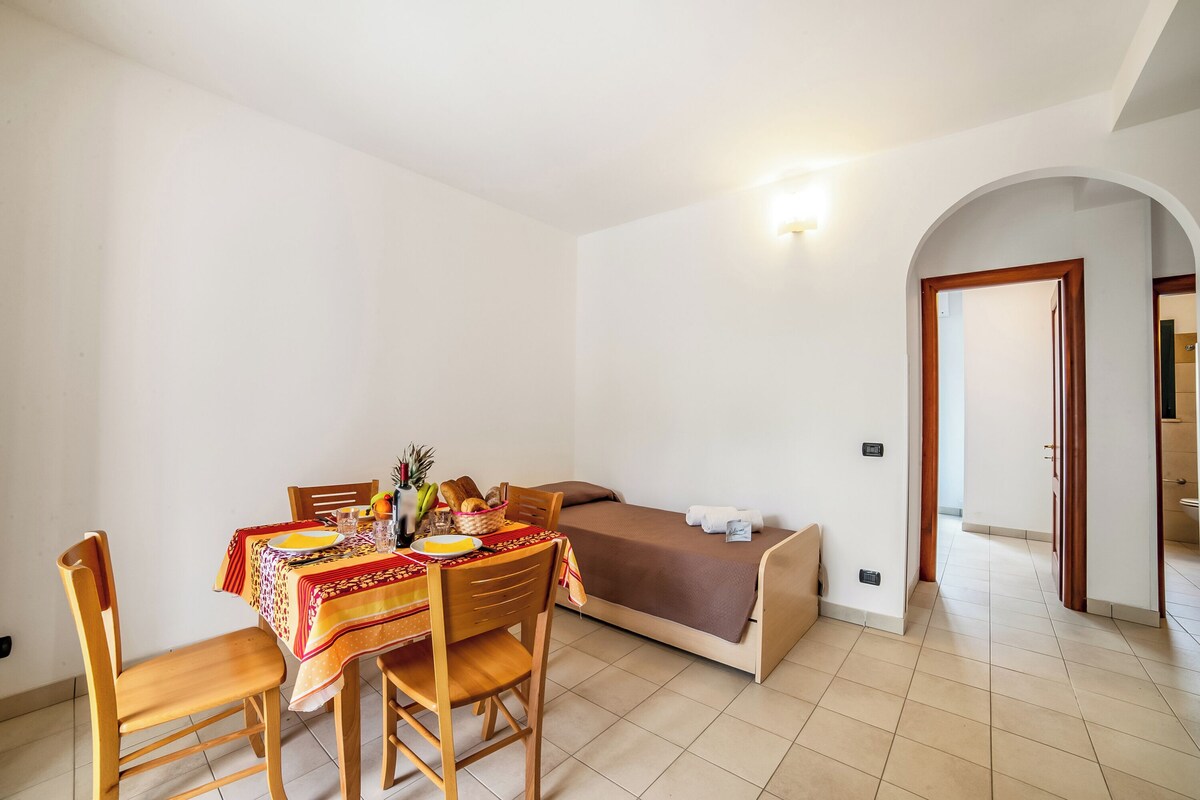 A small room with a bed, a table with chairs, and a tiled floor.