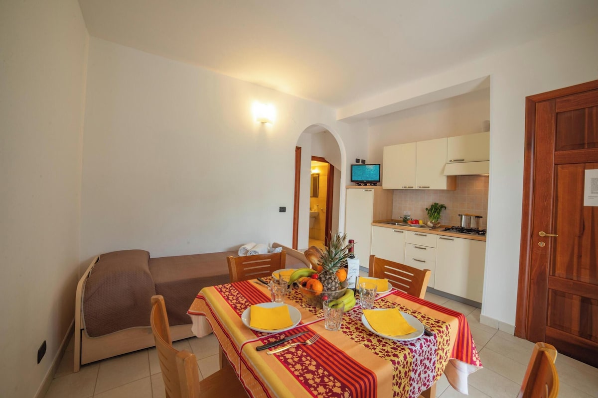 A dining area with a table set for four, a sofa, and a kitchen in the background.