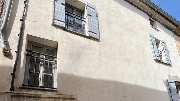 A building with a stone entrance, a window with metal bars, and a small balcony.