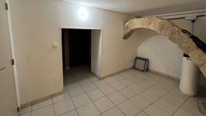 A room with a tiled floor, a doorway, a light fixture, and a stone archway.