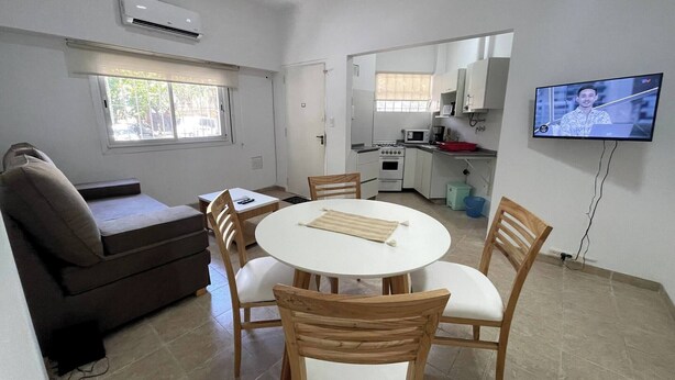 A compact living space with a dining area, kitchenette, and a TV mounted on the wall. - Comfortable Retreat Near River Plate's Monumental Stadium (Buenos Aires)