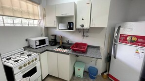 A compact kitchen with white cabinets, a gas stove, a microwave, a coffee maker, and a refrigerator. - Comfortable Retreat Near River Plate's Monumental Stadium (Buenos Aires)