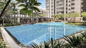 Une piscine entourée de verdure et de bâtiments modernes.