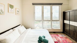 Une chambre d’hôtel avec un grand lit, une fenêtre avec des stores et une vue sur le paysage urbain.