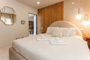 Une chambre d’hôtel moderne avec un grand lit, un mur décoratif en bois, un miroir rond et un luminaire au plafond.