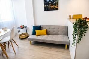 A modern living room with a sofa, a dining table, chairs, a small side table, a potted plant, and a framed picture on the wall. - Sun and beach in La Mata (La Mata)