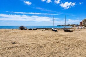 A sandy beach with several boats and a building in the background. - Sun and beach in La Mata (La Mata)