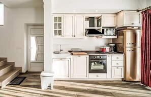 A modern kitchen with white cabinetry, a stainless steel oven, a microwave, and a red refrigerator. - Amazing home in Makarska with sauna (Makarska)