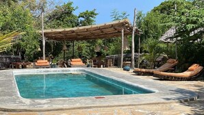 Ein rechteckiger Pool mit Liegestühlen und einer Holzpergola.