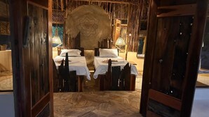 Ein Zimmer mit einem Bett, zwei Nachttischen, einem großen gewebten Kopfteil und Holzdielen.
