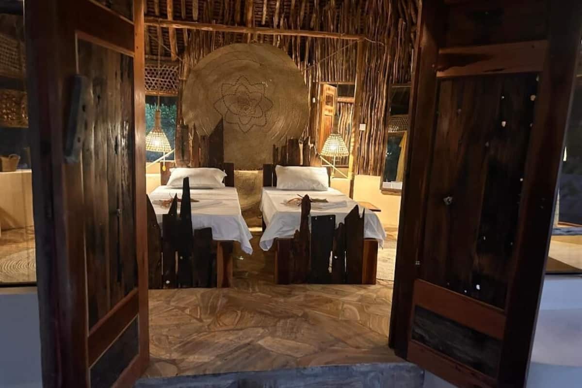 Una habitación con cama, dos mesitas de noche, un cabecero grande tejido y suelo de madera.