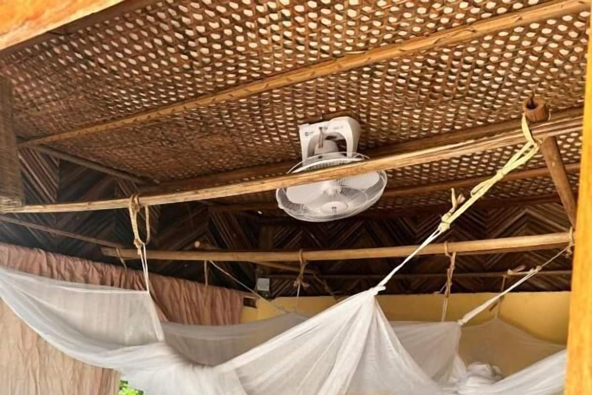 Una habitación con dos camas, una silla y una mosquitera.