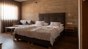 Un dormitorio moderno con una cama grande, un sofá, una mesita y suelo de madera.