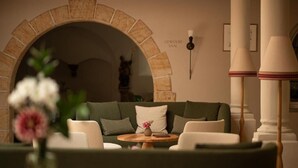 Un rincón acogedor con un arco de piedra, un sofá y una mesita con un florero.