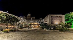 Un hôtel doté d’une cour intérieure, de plusieurs étages et d’une grande façade illuminée.