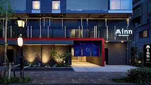 Un bâtiment moderne, reconnaissable à son enseigne distinctive indiquant qu’il s’agit d’une auberge, à sa façade rouge et noire et à son entrée bien éclairée.
