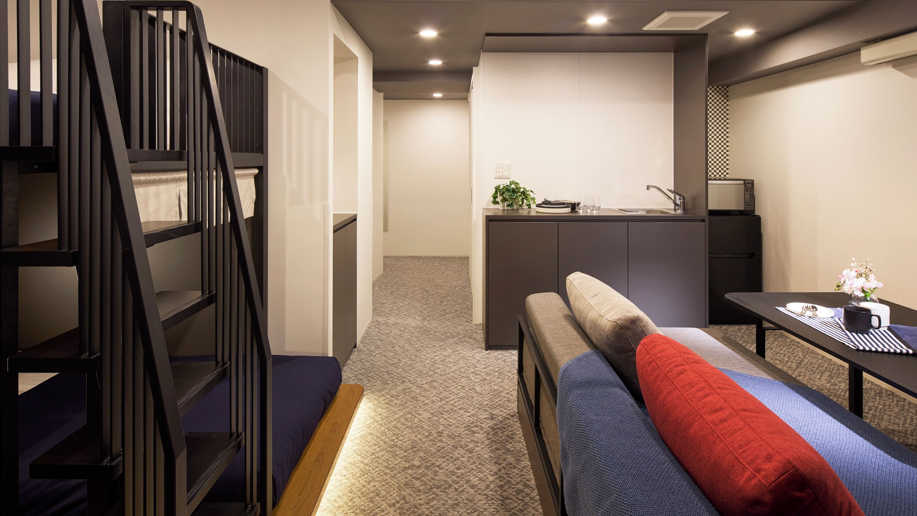 A compact room with a bunk bed, a kitchenette, and a small dining table.