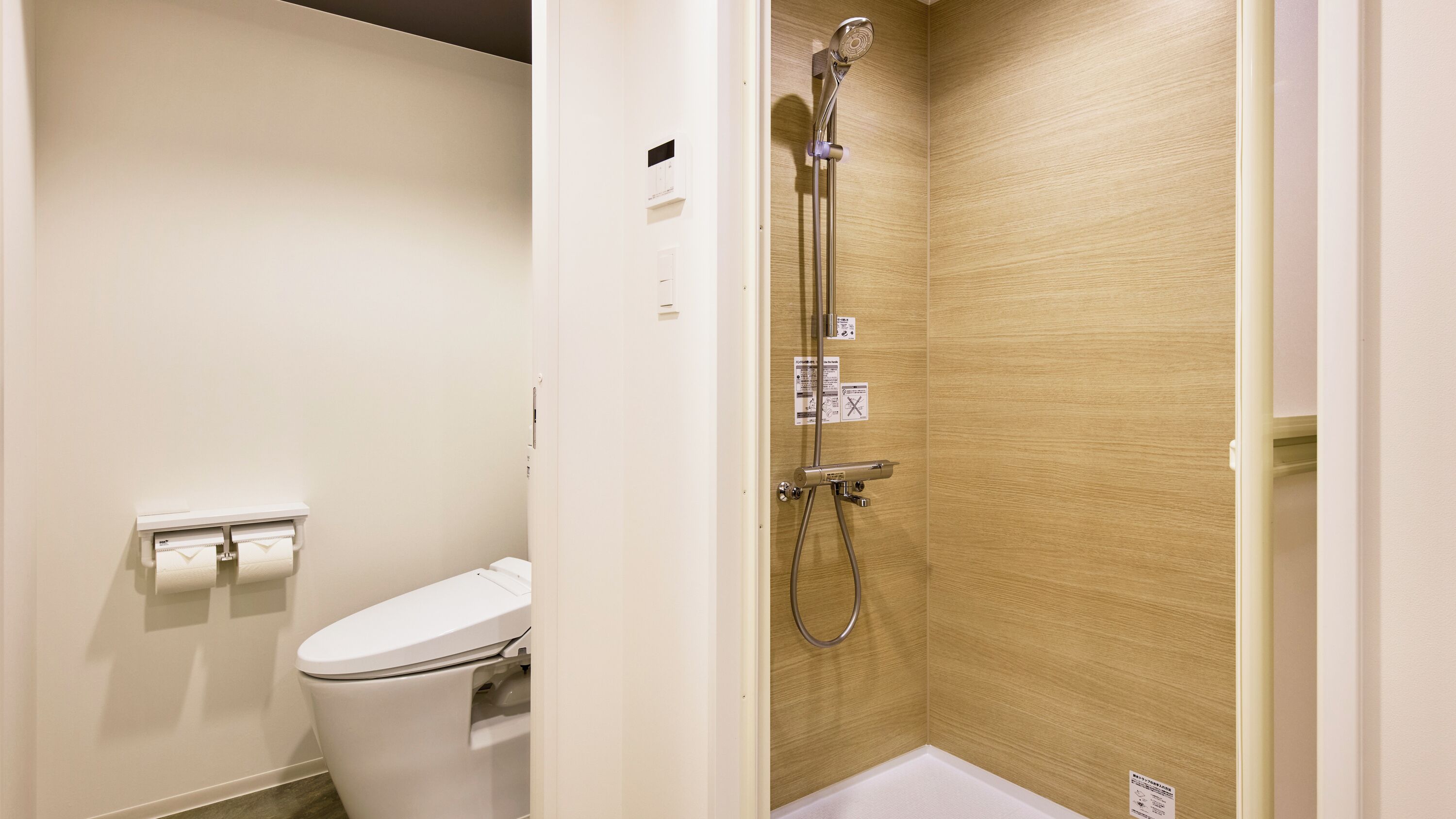 A bathroom with a toilet, a shower with a wooden wall, and a towel rack.