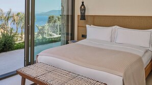 A modern hotel room with a large bed, a ceiling fan, and a view of a pool and mountains. - WAM by Karma (Bodrum)