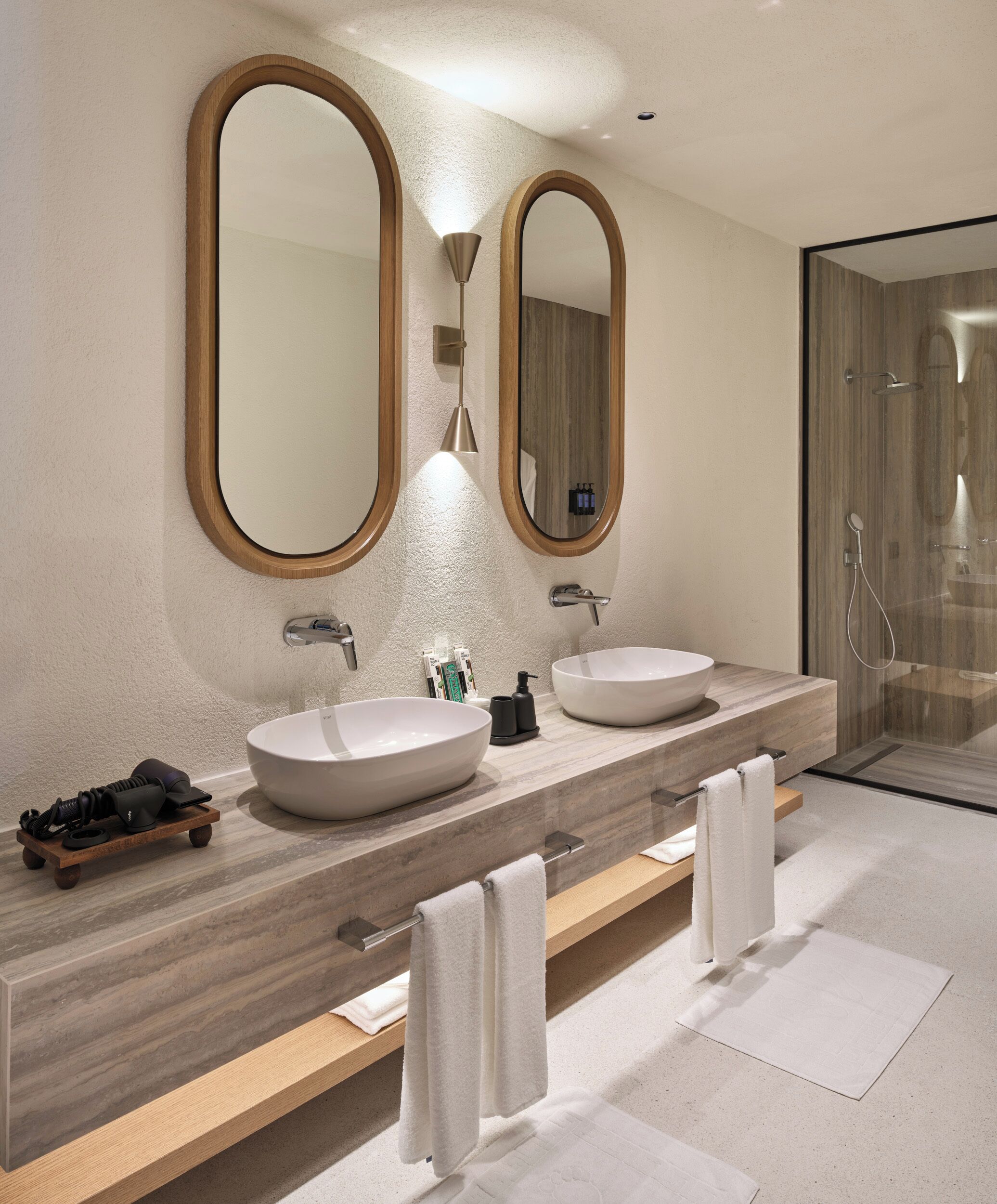 A modern bathroom with two sinks, a large mirror, and a shower.