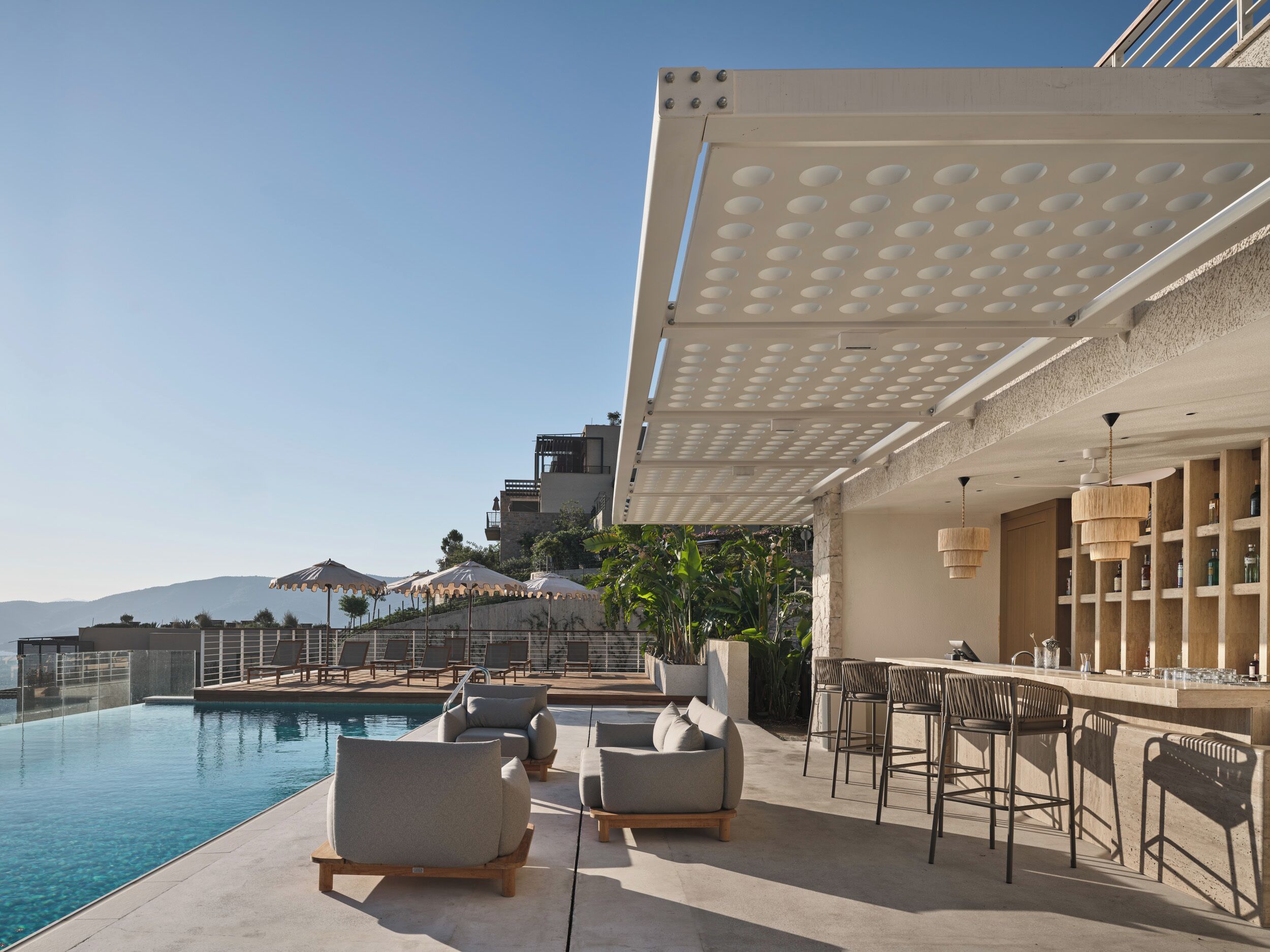 Ein Poolbereich mit Liegestühlen, einer Bar und einer Pergola.