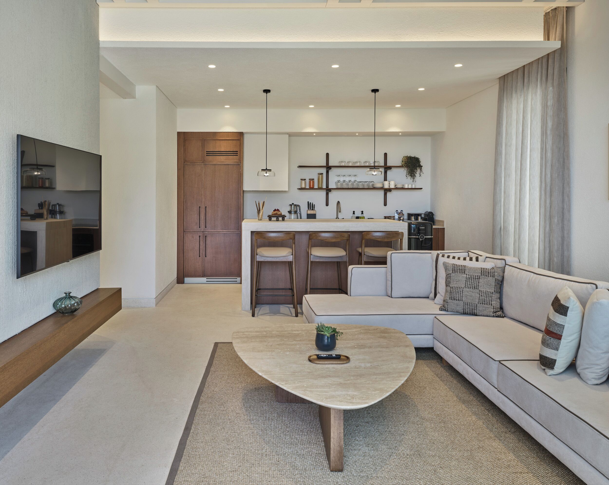 A modern living room with a sofa, coffee table, and a kitchen area with bar stools.