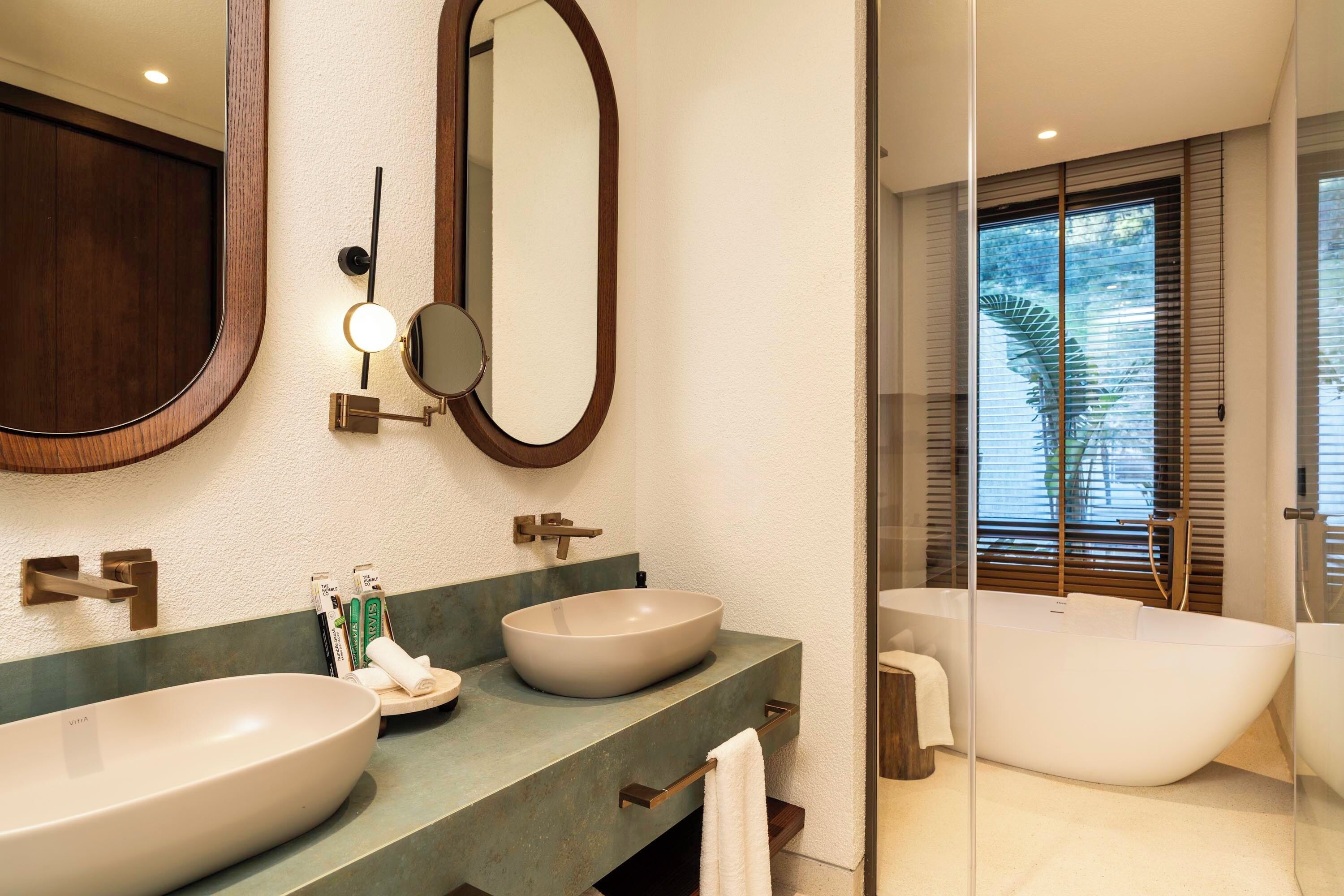 A bathroom with two sinks, a large mirror, and a freestanding bathtub.