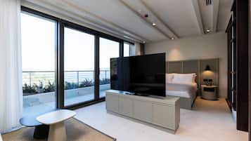 Ett modernt hotellrum med en stor TV, en säng, ett sängbord, ett litet bord och utsikt över omgivningarna.