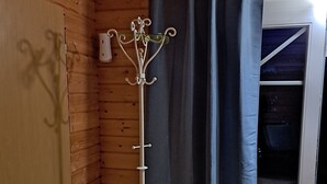 A wooden room with a coat rack, a curtain, and a sliding door.
