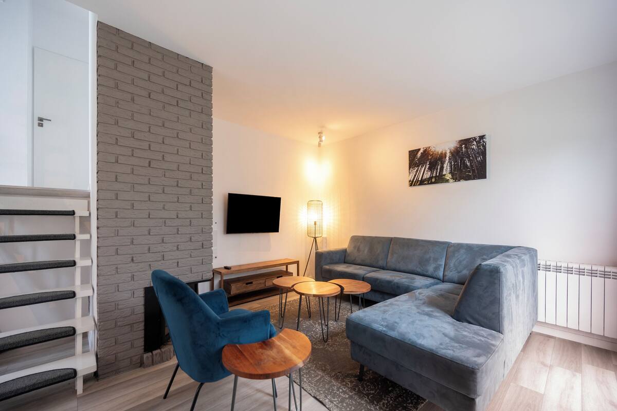 A modern living room with a grey sofa, blue armchair, and a wooden coffee table.