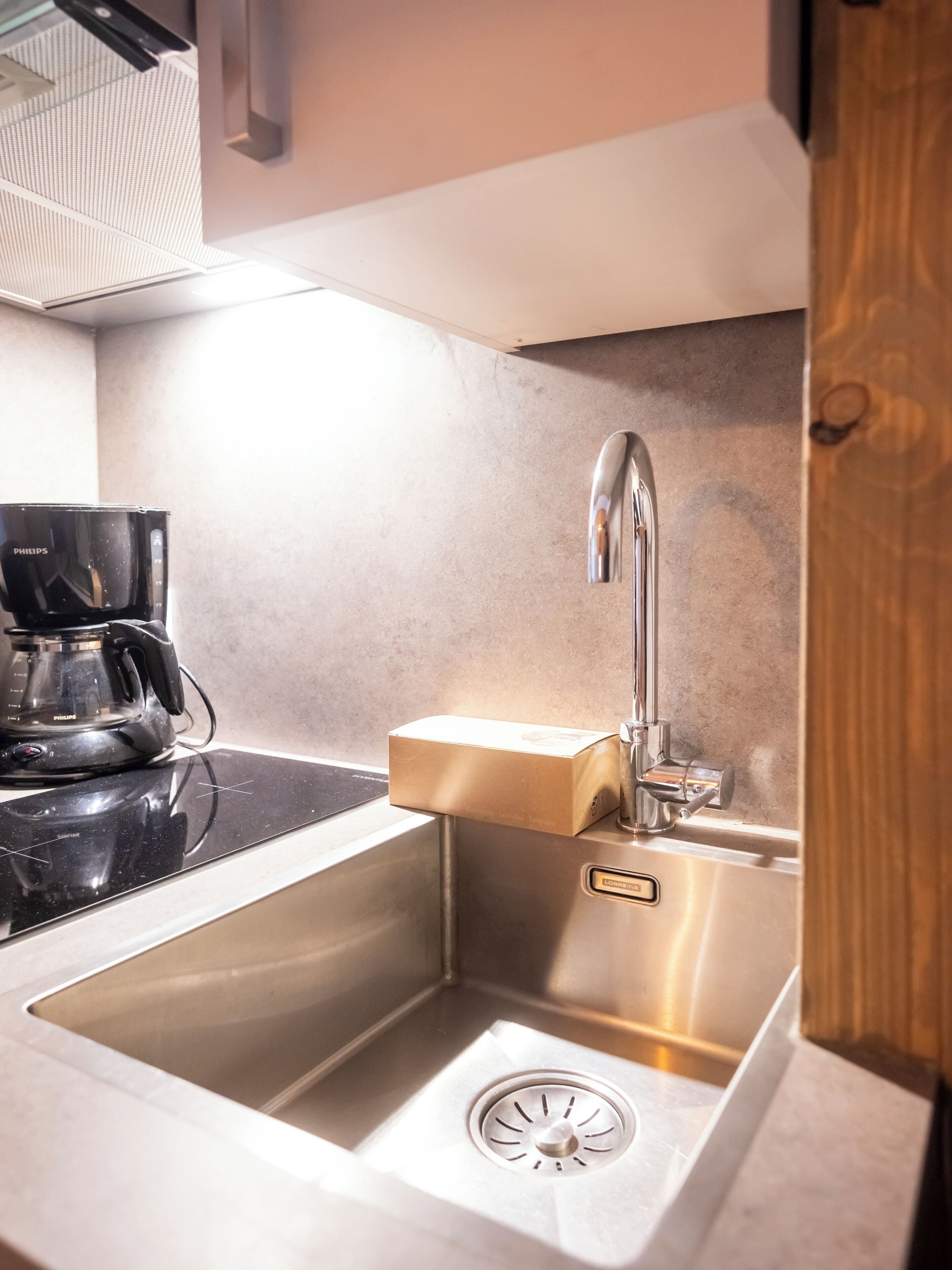 A modern kitchen with a stainless steel sink, a coffee maker, and a built-in oven.
