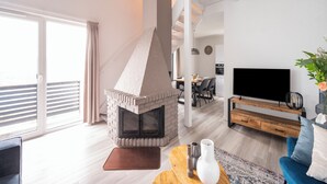 Ein modernes Wohnzimmer mit Kamin, Fernseher und Essbereich.